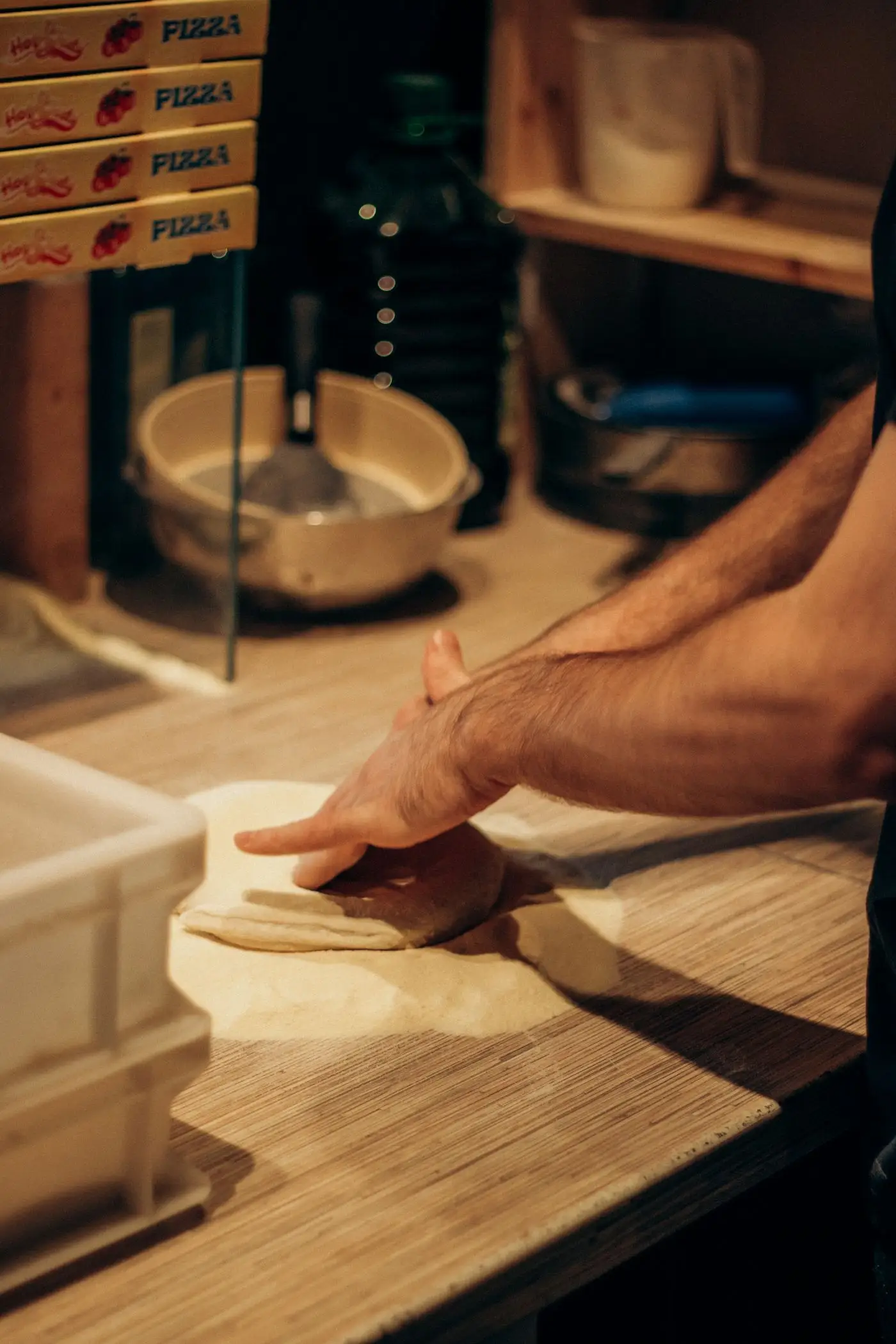 Une main presse un pâton sur le plan de travail fariné